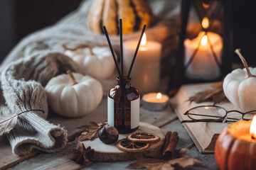 Home comfort, coziness, aromatherapy. Cozy fall interior with knitted wool warm sweater, burning candles and autumn aroma perfume diffuser. Pumpkin pie scent, maple sirup, cinnamon, anise, dry citrus