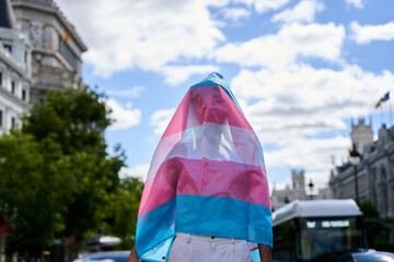 unrecognizable person covering himself with a transgender flag