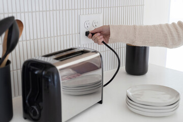 Plugging in a toaster. Toaster plugged in