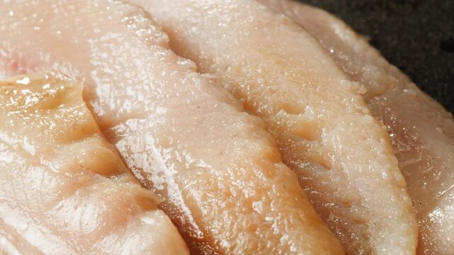Raw herring fish slices a black plate close-up macro. Marinated herring fillet in oil and spices for appetizer. Raw seafood products 