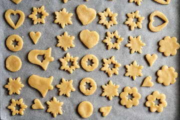 Shapes made of raw pastry dough on a sheet of baking paper - preparation of Linzer Christmas cookies
