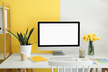 Modern PC, beautiful narcissus flowers, houseplant, coffee, notebook and paint color palettes on...
