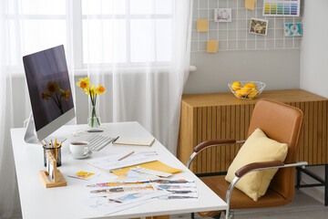 Comfortable designer's workplace with modern PC and beautiful narcissus flowers near window