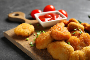 Board with delicious nuggets and ketchup on black table, closeup