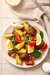 Plate of tasty potato salad with eggs and tomatoes on light background, top view