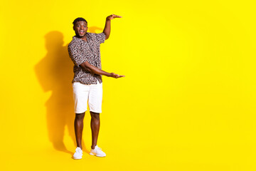 Photo of positive glad cheerful man wear trendy clothes hold empty space isolated on vibrant yellow color background