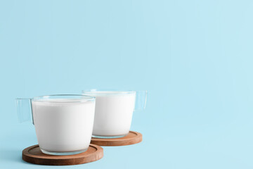 Glass cups with fresh milk on blue background