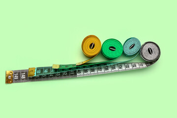 Colorful measuring tapes on green background