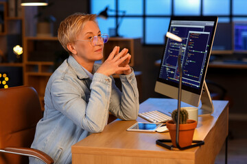 Mature female programmer working in office at night