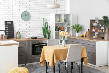 Interior of modern kitchen with blooming narcissus flowers in vase on table