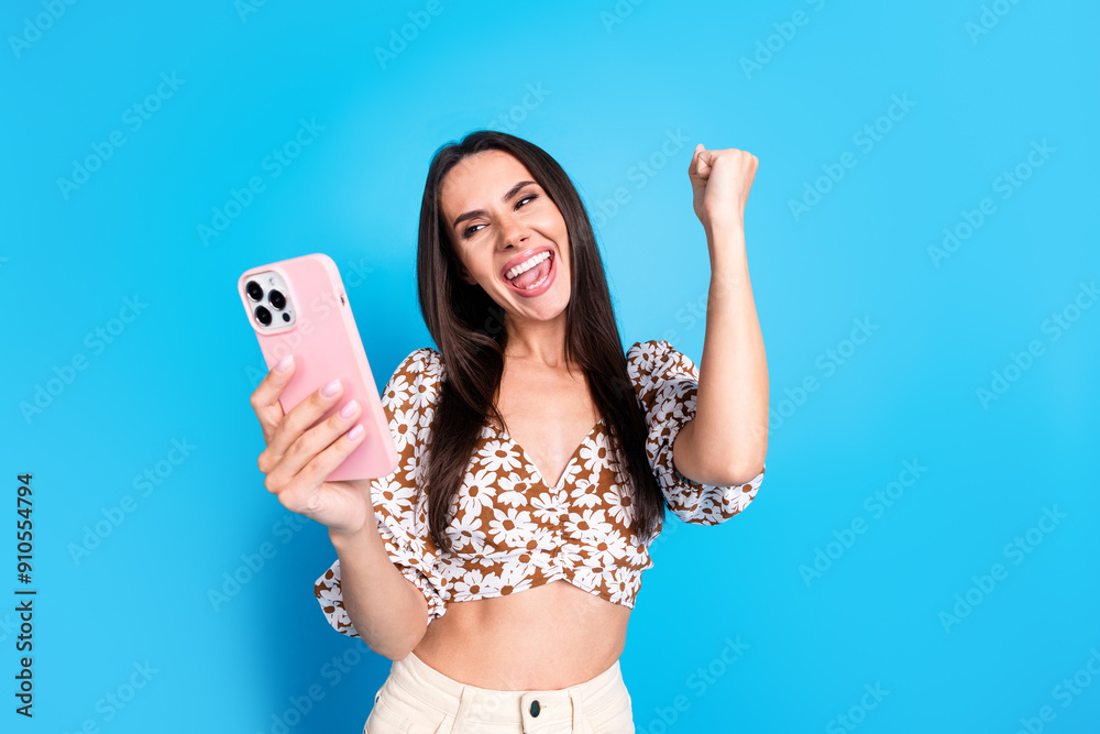 Wall mural Photo of overjoyed glad gorgeous woman wear trendy summer print clothes raise hand fist isolated on blue color background