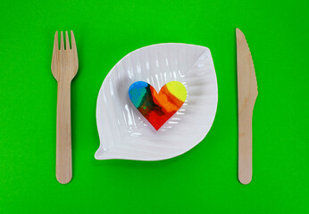 Plate with colorful heart next to disposable wooden cutlery