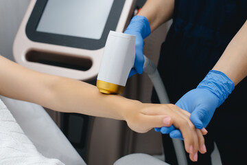 laser epilation, hair removal procedure, young beautiful caucasian smiling brunette woman lying on couch in beauty salon, arm epilation, spa and cosmetology concept