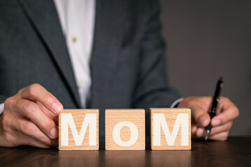 There is wood cube with the word MoM. It is an abbreviation for month over month as eye-catching...