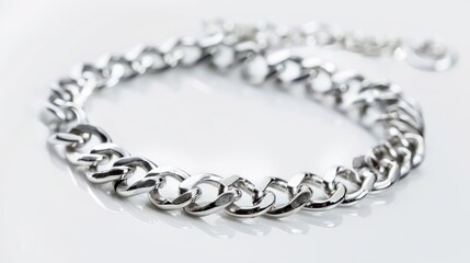 Obraz premium Shiny silver chain bracelet gleams on a white surface, exuding elegance and style. Perfect for a luxurious and fashionable collection