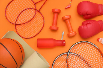 Sport equipment with dumbbells and rackets on orange background. Top view