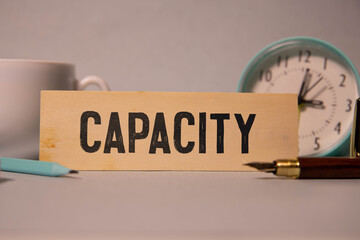 CAPACITY text on a strip of wood lying on a white table.