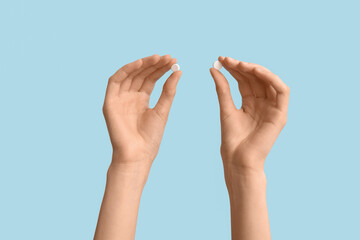 Female hands with pills on blue background