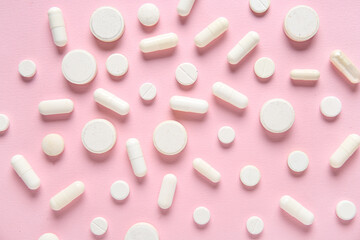 Different white pills on pink background, closeup
