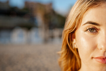 Obraz premium Portrait of one happy young beautiful woman smiling looking at the camera with big blue and green eyes. Female girl at the beach close up face.