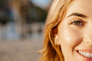 Obraz premium Portrait of one happy young beautiful woman smiling looking at the camera with big blue and green eyes. Female girl at the beach close up face.