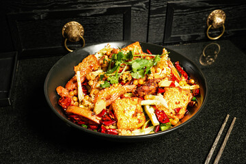Spicy hot pot with tofu, seafood, shrimp, red chilli, coriander and chopsticks served in dish on dark background top view of hong kong food