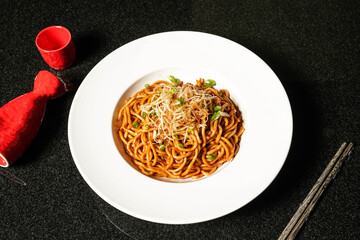 Noodles in Soy and Scallion Oil with chopsticks served in dish on dark background top view of hong kong food