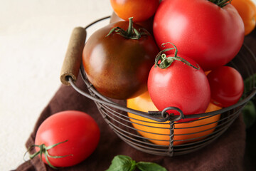 Tomatoes in bowl on cloth on table against white background. Closeup