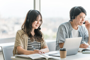 ヘッドセットをつけて通信教育・英会話教室・Web会議・オンライン授業・勉強をする大学生・高校生
