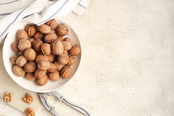 Bowl with tasty walnuts and nutcracker on white background
