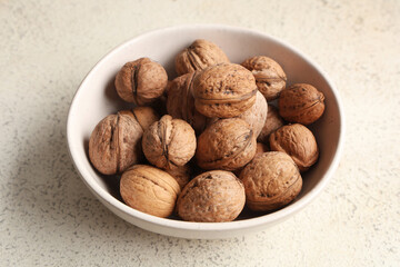 Bowl with tasty walnuts on white background