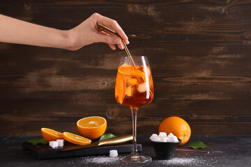 Female hand with glass of Aperol spritz cocktail and sugar on black table