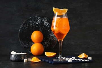 Glass of Aperol spritz cocktail with fruits and sugar on black background