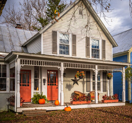 Charming old house during autumn with orange doors, decorated with pumpkins for fall season and Halloween. Photo taken in Montgomery Center, Vermont, New England, United States in October 2023.