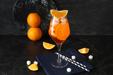 Glass of Aperol spritz cocktail with fruits and sugar on black background