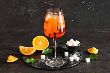 Glass of Aperol spritz cocktail and bowl with sugar on black background