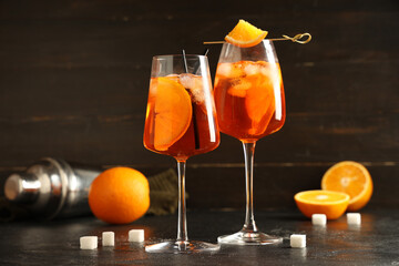 Glasses of Aperol spritz cocktail with shaker and sugar on black table