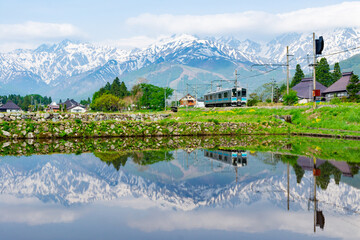 残雪の山々を背景に駆け抜ける大糸線