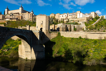 Impressive view of ancient Alcazar of Toledo palace and Alcantara bridge over Tagus river, at capital of province of Toledo in central Spain