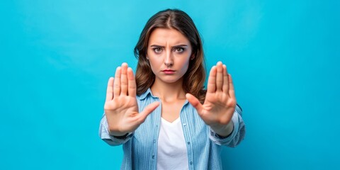Serious female hands forming a prohibition sign against a bright blue background, conveying a strong message of restriction, rejection, or disapproval.