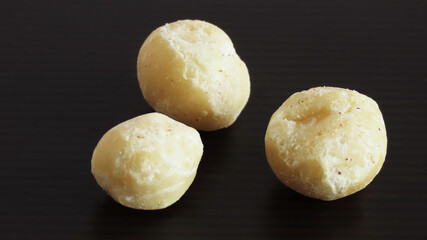 Roasted macadamia nuts gruop on black and brown striped background
