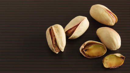 Roasted pistachio nuts in shell on black and brown striped background
