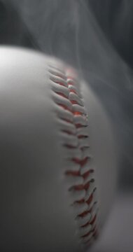 Baseball ball close-up rotating with smoke in studio slow motion, vertical view