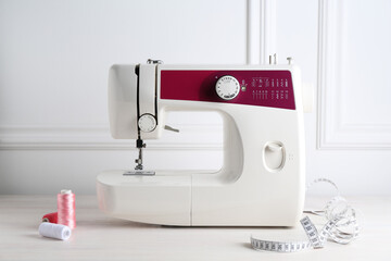 Sewing machine and craft accessories on white wooden table indoors