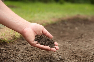 Woman holding pile of soil outdoors, closeup. Space for text