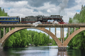 Retro steam train moves above the river.