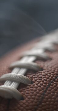 Football ball macro rotating with smoke in studio slow motion, vertical view