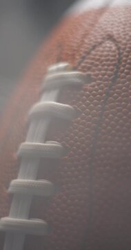 Football ball macro rotating with smoke in studio slow motion, vertical view