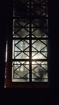 A solitary ray of morning sunlight pierces through a dusty window, illuminating a darkened room with a warm, golden glow.
