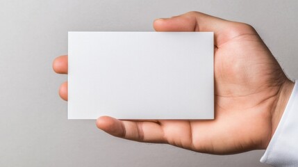 Fototapeta premium A person holds a blank white business card ready for potential networking or introduction.